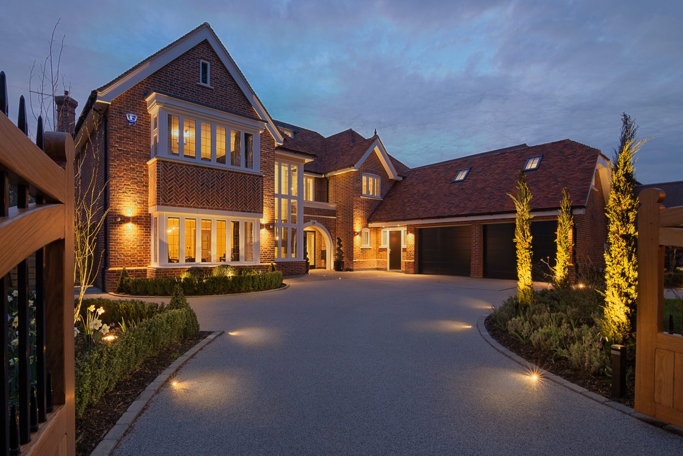 Brick family house at dusk with lit windows and driveway